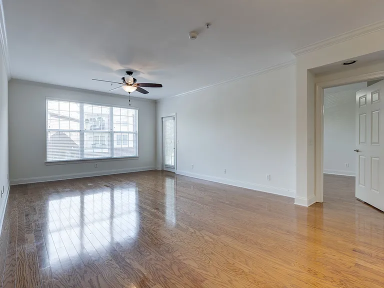 Large living Area with High Ceilings features triple windows for lots of natural light. The Door on the right leads to the Primary Bedroom.