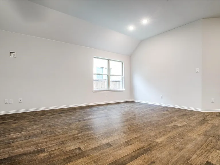 Spacious interior featuring wood-finish flooring, vaulted ceilings, and recessed lighting