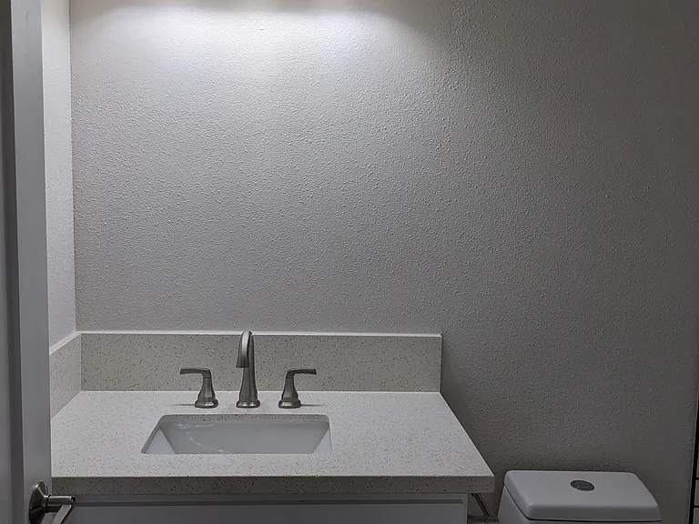 Lots of bathroom lighting and white fixtures at The Hardison Apartments in Pasadena, California.