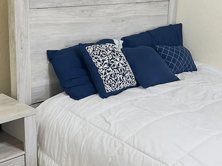 Furnished bedroom featuring a sturdy bed with headboard, matching nightstand, and fresh linens for comfortable living.