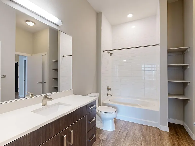 Apartment bathroom with large soaking tub and wood-style flooring.