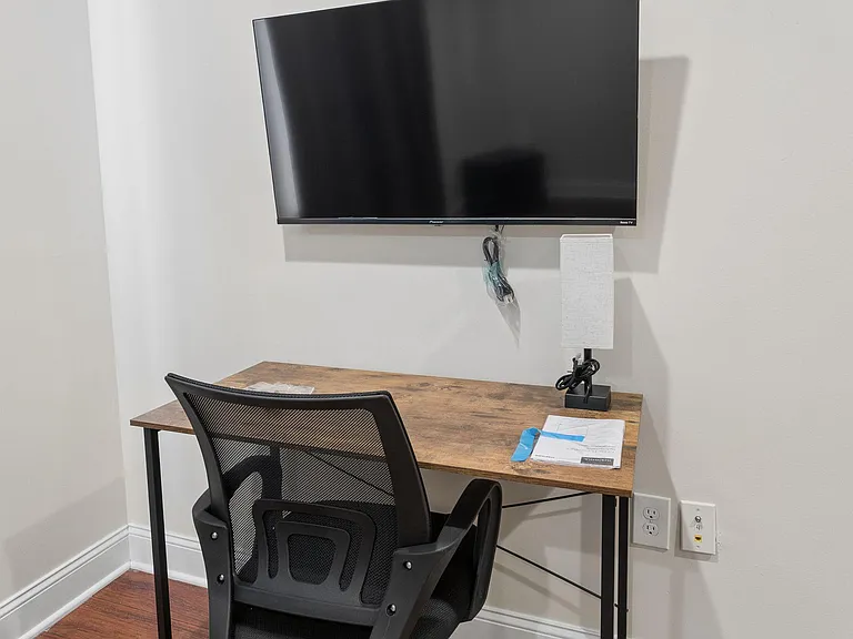 Dedicated work nook with a spacious desk, ergonomic chair, task lighting, and a wall-mounted TV for easy streaming.