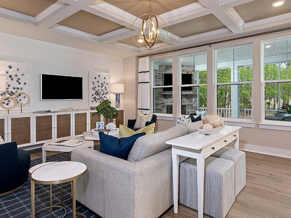 Living room with quadruple window, coffered ceiling and seating in a DRB Homes Barbados model home i