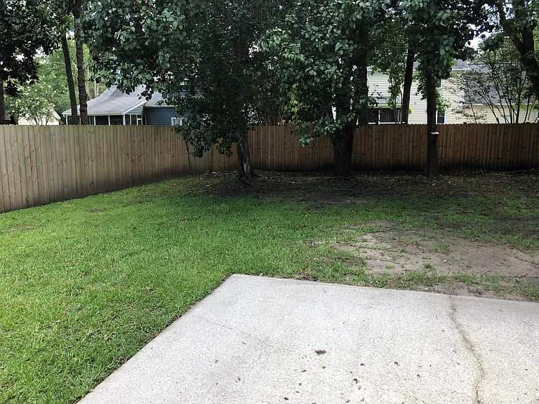 Back patio with privacy fence and mature shade trees.