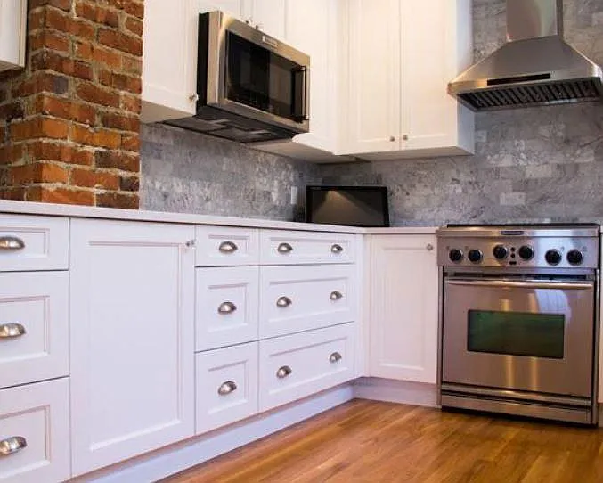 Chef's kitchen with marble and exposed brick. Gas stove and stainless appliances.