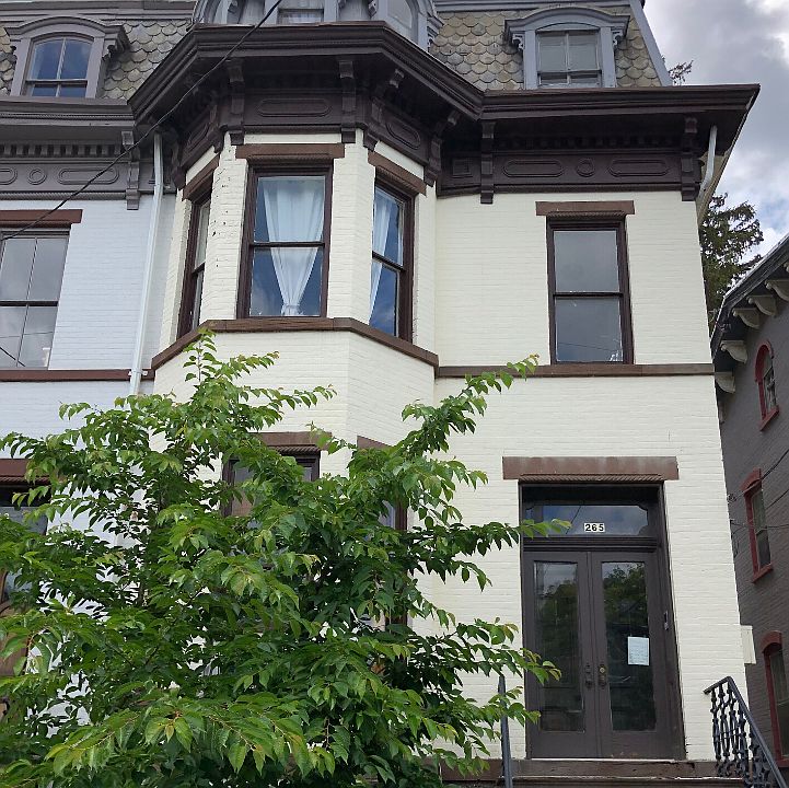 The Second French Empire style brownstone is flanked by a pink-flowered cherry tree underplanted with roses, peonies and daffodils.