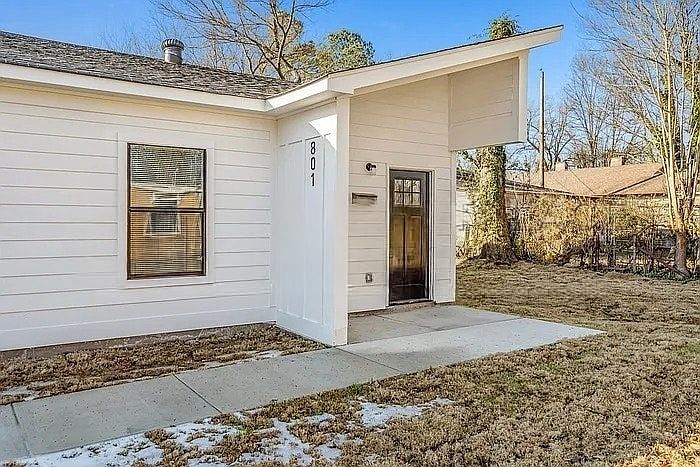 A contemporary entrance defined by sharp architectural angles, crisp white horizontal siding, and a contrasting dark wood door.