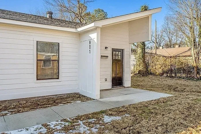 A contemporary entrance defined by sharp architectural angles, crisp white horizontal siding, and a contrasting dark wood door. - 803 Goodwyn St #801