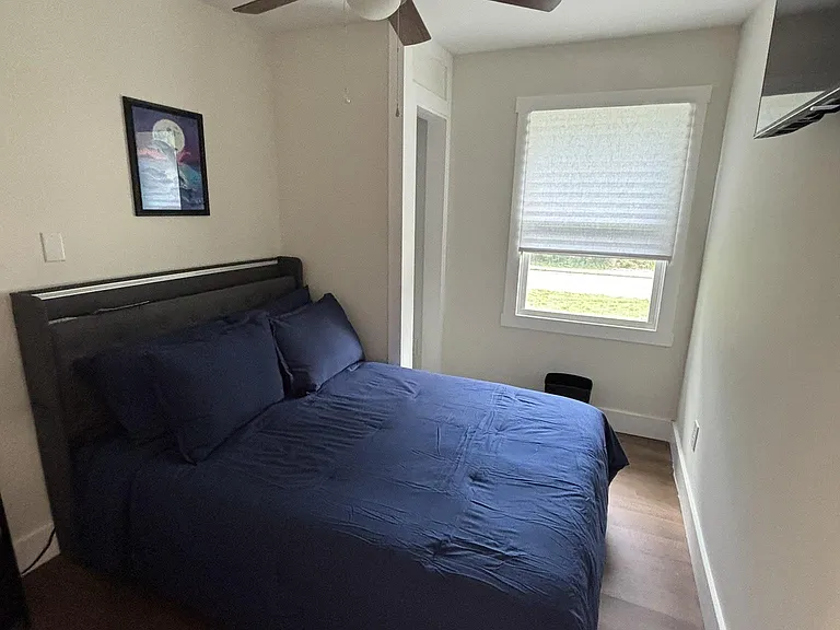 Furnished bedroom with a double bed, ceiling fan, and a window with shade for natural light and privacy.