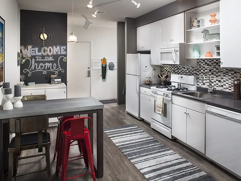 Classic Package I kitchen with white appliances, dark laminate countertops, white cabinetry, tile backsplash, and hard surface flooring