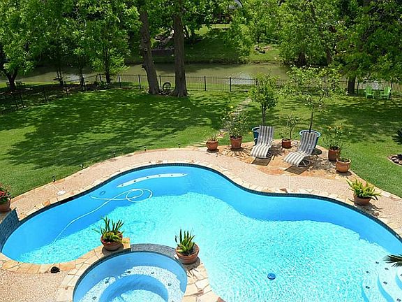An astonishing free form pool and spa overlook natural Pecan Lake for a jaw-dropping visual.  A full wrought iron fence encircles the lush green lawn without hindering the view.