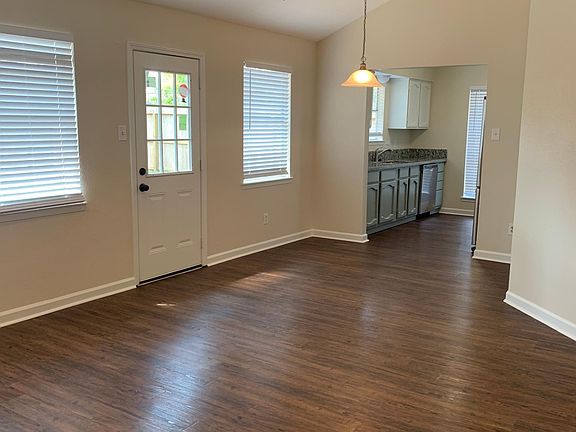 View from living room into dining room and kitchen. Door between living and dining leads to large backyard.