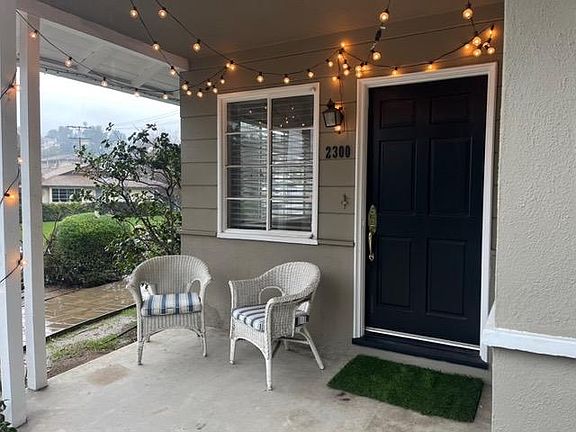 Charming front patio overlooking beautiful landscaped front yard with rose bushes lining the pathway