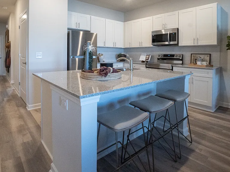 View of the kitchen and entry hallway. Offering bar seating, plenty of cabinet space and granite countertops.