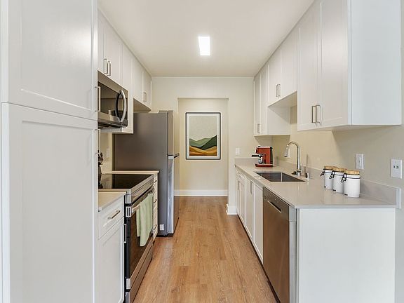 Renovated Package I kitchen with beige granite countertops, white cabinetry, stainless steel appliances, and hard surface flooring