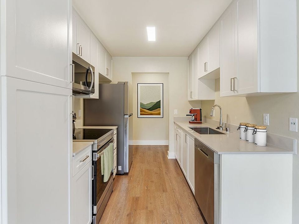 Renovated Package I kitchen with beige granite countertops, white cabinetry, stainless steel appliances, and hard surface flooring