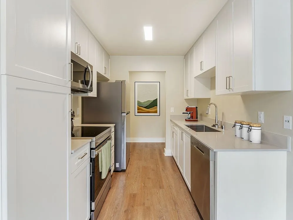 Renovated Package I kitchen with beige granite countertops, white cabinetry, stainless steel appliances, and hard surface flooring - eaves Lake Forest