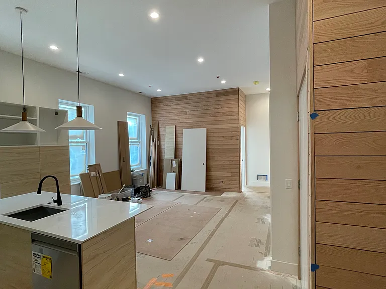 In-progress photo of kitchen/living room, taken from the entry way. Features wood walls.