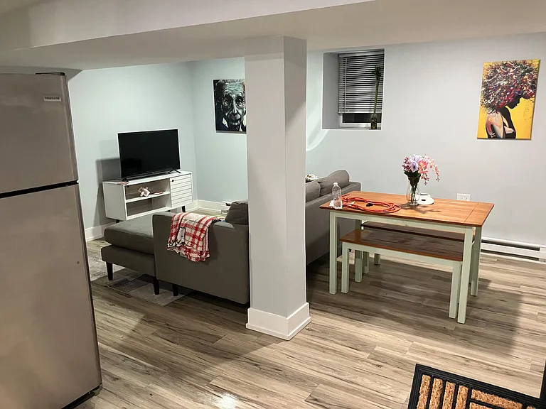 Open common area with a lounge setup, TV stand, and adjacent dining tableideal for relaxing and shared meals.