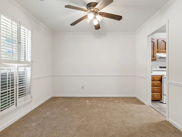 Formal dining area featuring plantation shutters, crown molding, chair rail, and ceiling fan