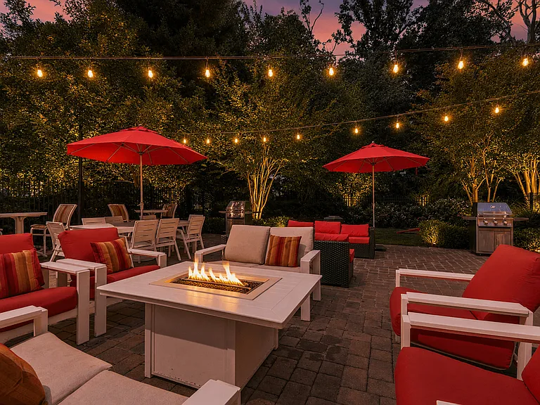 A patio with red chairs and a fire pit.