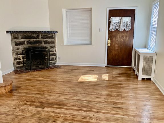 Living room with working wood fireplace and freshly refinished hardwood floors.
