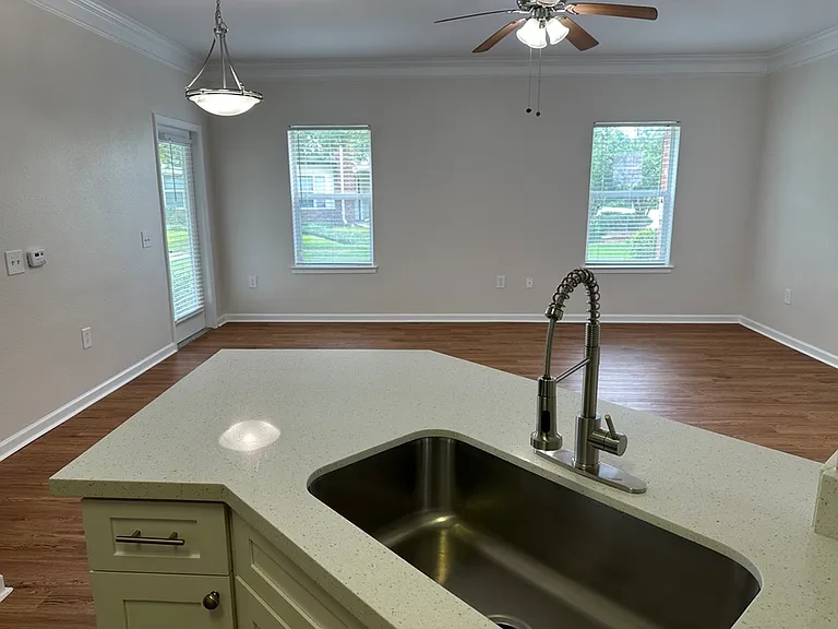 Bright open-concept living area with wood-style floors, modern quartz kitchen island, and large windows offering natural light. Bright open-concept living area with wood-style floors, modern quartz kitchen island, and large windows offering natural light.