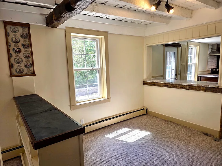 Living area is divided into two rooms by a built-in bookcase with slate bar top. A small preserved section of original wallpaper is featured among reclaimed chestnut and walnut which proudly represents this property's colonial heritage.
