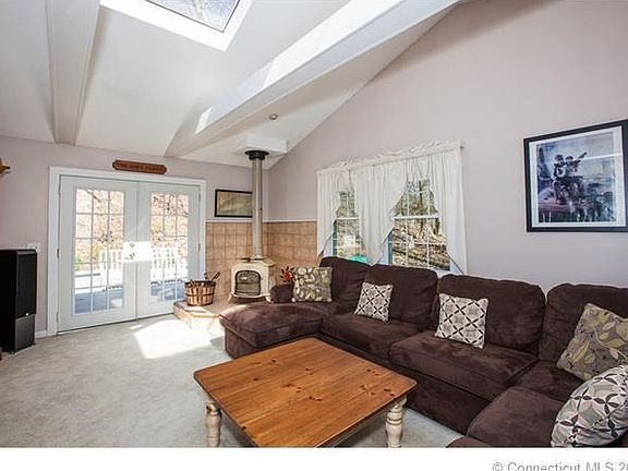 Living room has vaulted ceilings with beams, wood stove and French doors which lead to the backyard deck