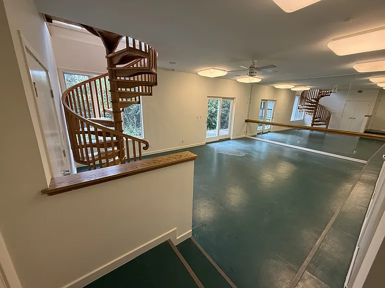 A spiral staircase leading down from the primary suite to an exercise studio.

Exercise studio features a mirrored wall, multiple storage closets and a patio door to a cozy deck and the wrap around hanging walkway.