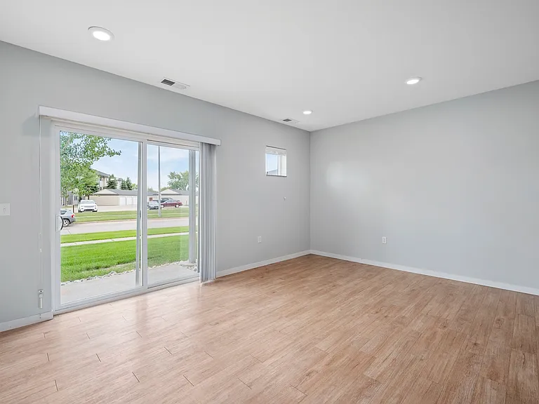 Bright and spacious living room with large sliding glass doors leading to a scenic outdoor view, featuring elegant wood flooring and modern recessed lighting. Bright and spacious living room with large sliding glass doors leading to a scenic outdoor view,
