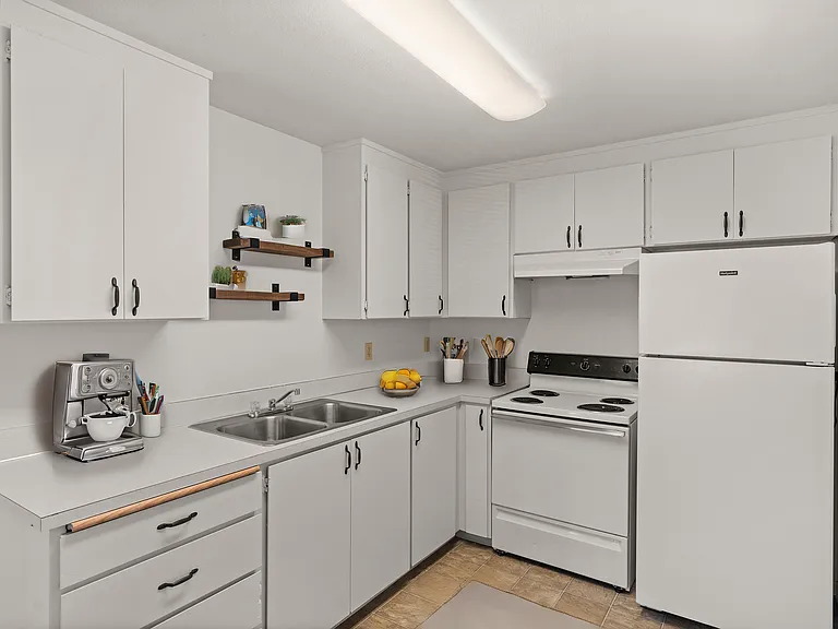 Bright and modern kitchen with white cabinetry, sleek countertops, and elegant open shelving, featuring a stylish coffee machine and essential appliances. Bright and modern kitchen with white cabinetry, sleek countertops, and elegant open shelving, featur