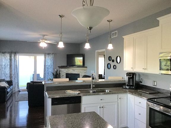 Gourmet kitchen with hardwood floors, staggered enameled cabinetry, pantry, center island, peninsula with upgraded Cambria tops and open to the dining area