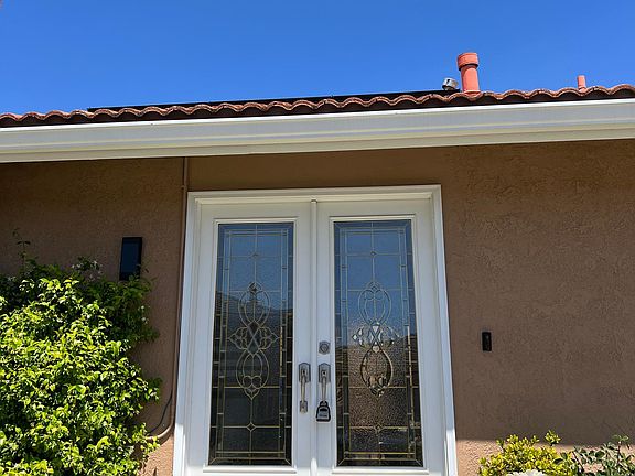 Double etched front doors surrounded by rose bushes leading to front door