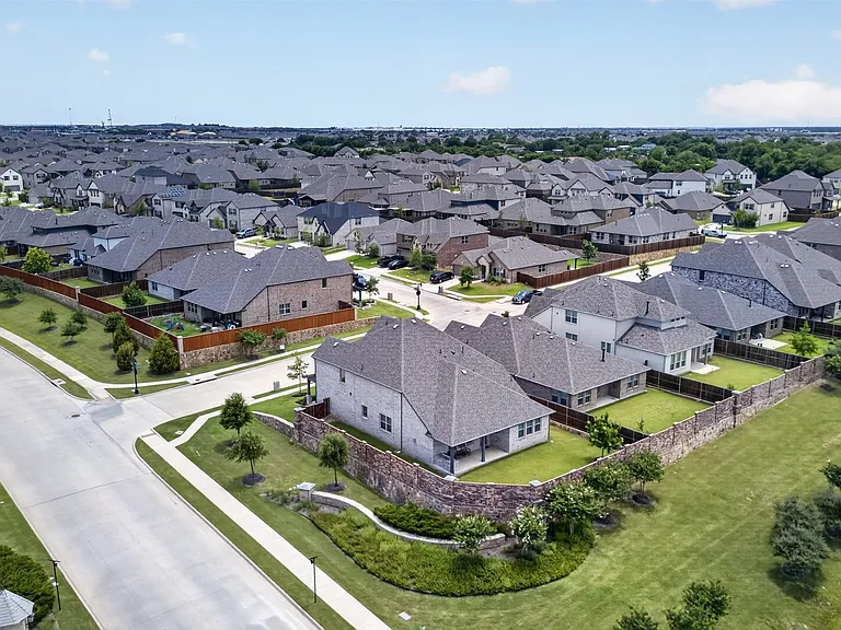 Expansive residential development featuring a collection of single-family homes with pitched roofs, individual backyards, and established landscaping
