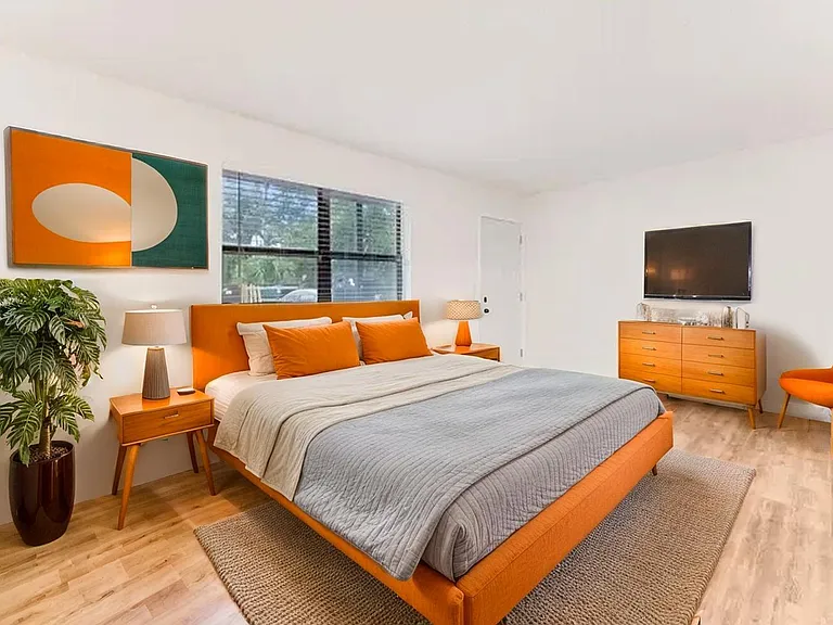 Inviting bedroom with modern orange accents, featuring a comfortable bed, stylish decor, and warm lighting. Inviting bedroom with modern orange accents, featuring a comfortable bed, stylish decor, and warm lighting.