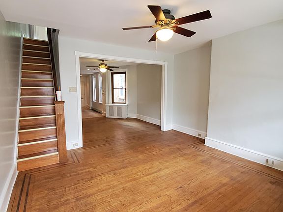 Light-filled living room with ceiling fan and beautiful hardwood floors.