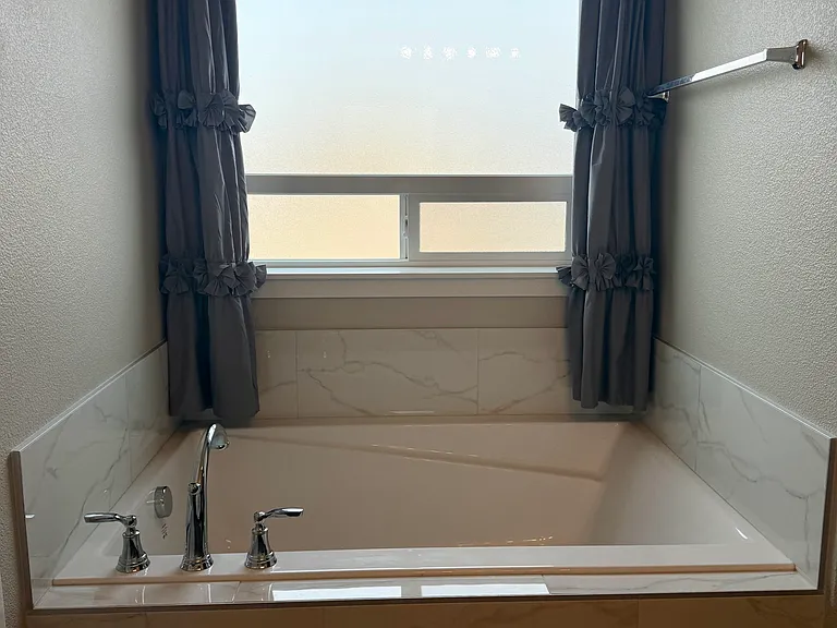 Relaxing soaking tub with frosted window in the primary bathroom.
