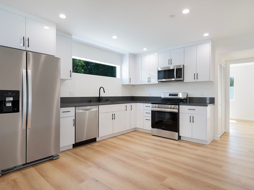 Brand new modern kitchen with sleek white cabinets, black quartz countertops, and top-of-the-line stainless steel appliances.