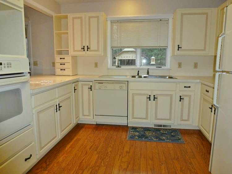 Efficient kitchen with off-white cabinets, hardwood floors and a large pantry.