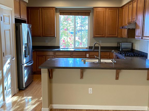 Kitchen with stainless steel appliances: vent, microwave, gas stove, countertop oven, dishwasher, and refrigerator