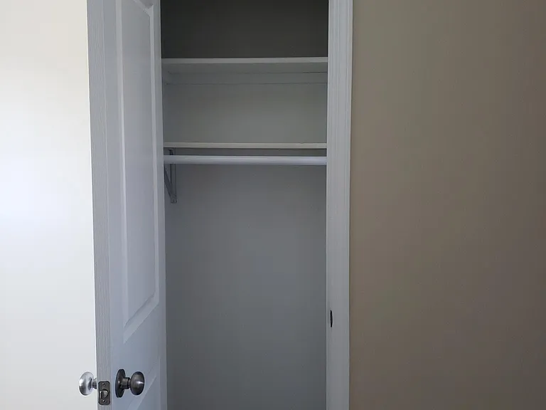 Coat closet off Living Room with 2 storage shelves