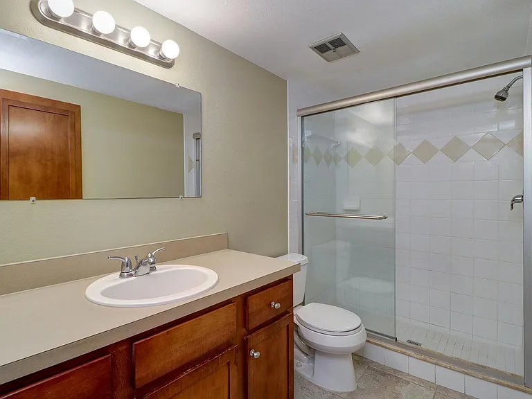 Bathroom has a large vanity with extra storage, built in medicine cabinet and glass enclosed shower