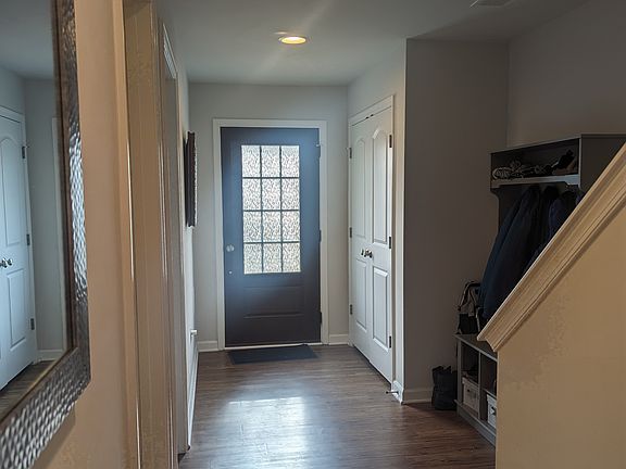 Bottom floor landing from view of 2-car garage towards front door with coat closet and hall tree