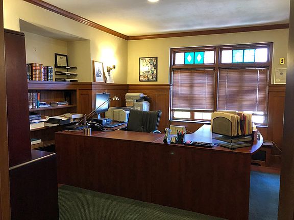 Office with large desk and built in bookcases, wainscoting and stain glass windows.