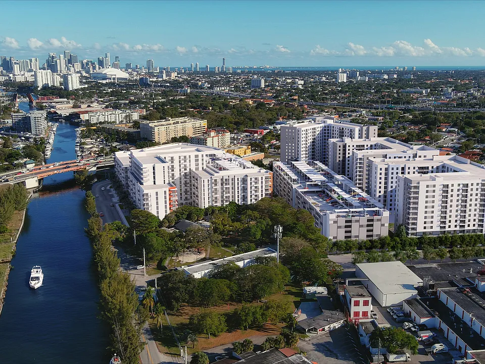 Stunning aerial view of modern apartment homes beside a serene canal in a vibrant cityscape, offering urban luxury and waterfront tranquility.