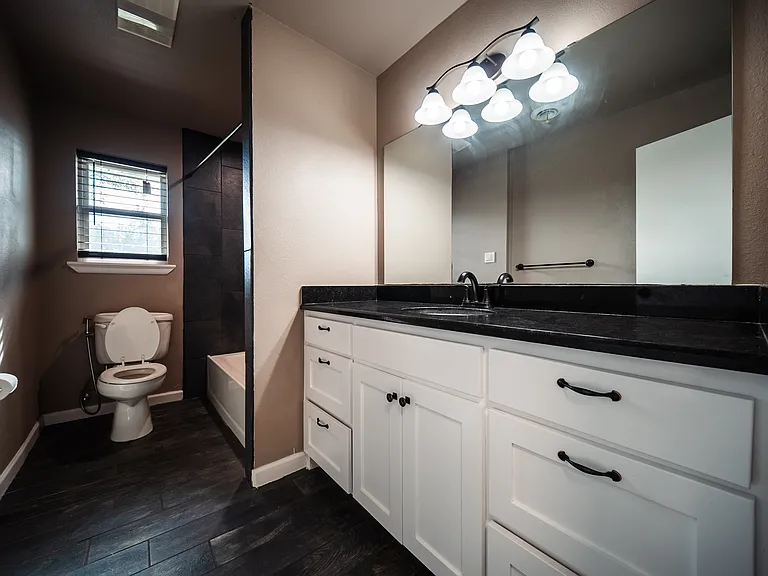 Updated bathroom with modern vanity, dark countertop, and stylish lighting