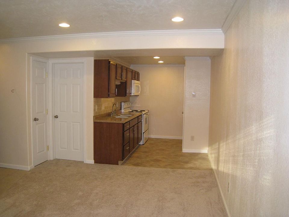 View of the kitchen, with the pantry to the right, of the sink area, from the living room. The doors to the left, outside the kitchen, are the closet and the bathroom.