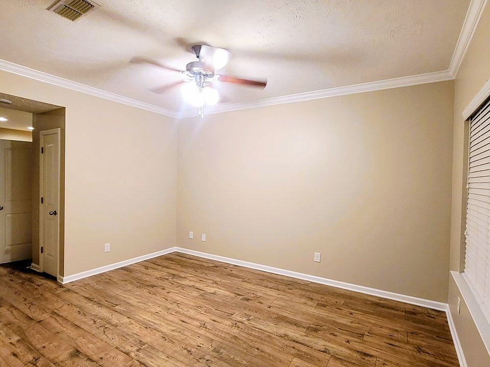 Living room with plank vinyl flooring, large picture window, blinds & ceiling fan