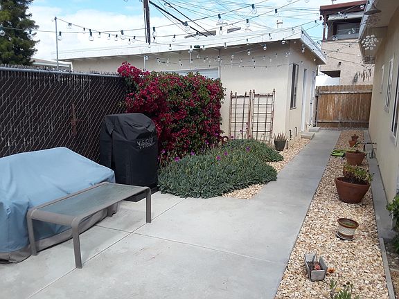 This photo shows a building on left of sidewalk which includes a laundry room and 2 garages (one per unit). Parking spaces are located in front of the garages. This patio is similar to the available unit's patio.